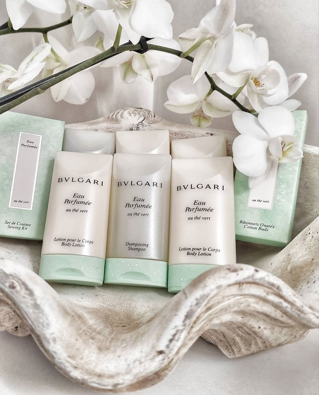 Σετ προϊόντων BVLGARI Eau Parfumée με λευκά μπουκάλια, πράσινη βάση, και λευκά άνθη ορχιδέας.